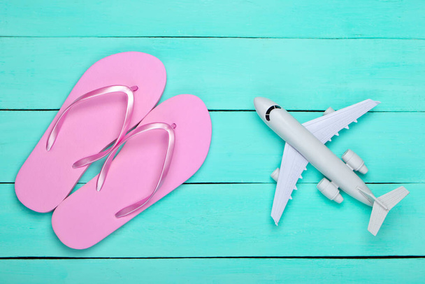 Flat lay composition of beach vacation, resort and travel. Flip flops, airplane on blue wooden background. Top view - Photo, Image