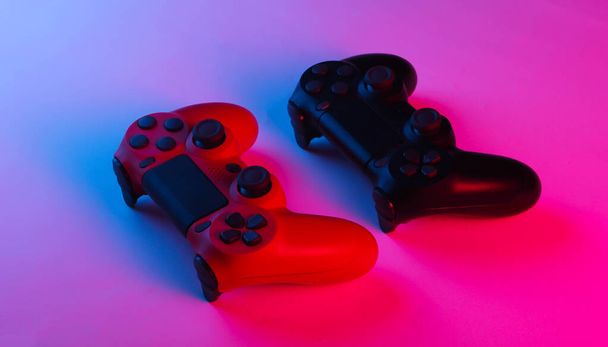 Twee Gamepads met neon blauw-roze licht. Gamingconcept. - Foto, afbeelding