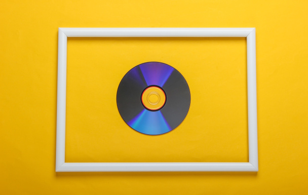 Sarı arkaplanda beyaz çerçeveli CD disk. Üst görünüm - Fotoğraf, Görsel
