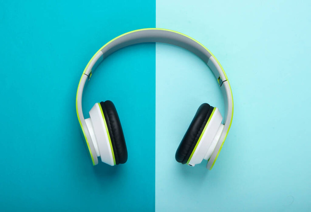 Elegantes auriculares estéreo inalámbricos sobre fondo azul pastel. Amante de la música. Gadgets. Vista superior. - Foto, Imagen