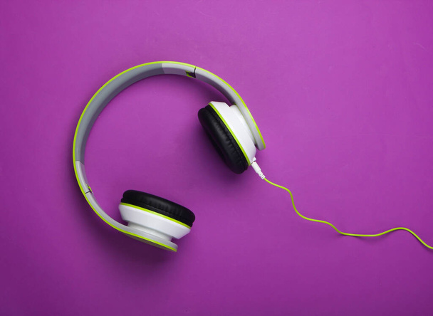 Stylische kabelgebundene Stereo-Kopfhörer auf lila Hintergrund. Musikliebhaber. Gadgets. Ansicht von oben. - Foto, Bild