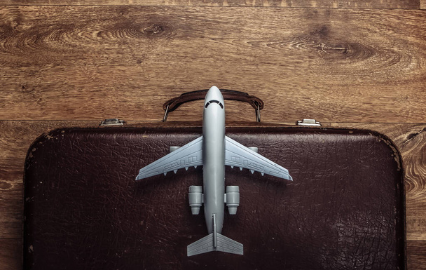 Travel concept. Old luggage and airplane figurine on wooden floor. Flight voyage, trip, journey. Flat lay composition. Top view - Photo, Image