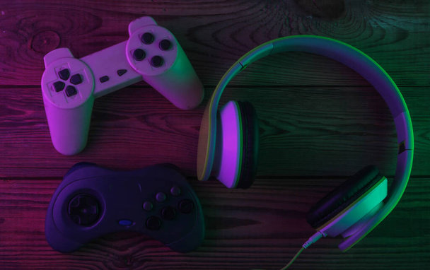 Stereo koptelefoon met retro gamepads. Neon paars groen licht. Gokconcept. Gradiëntgloed. 80-er jaren. Bovenaanzicht - Foto, afbeelding