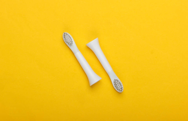 Verwisselbare mondstukken van elektrische tandenborstel op een gele achtergrond - Foto, afbeelding