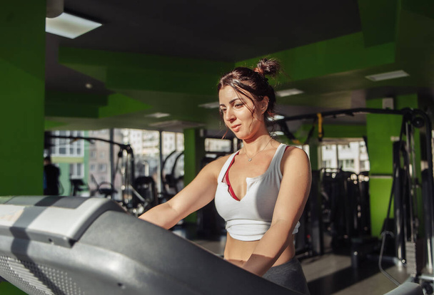 Fröhliche schlanke Frau in Sportbekleidung auf einem Laufband im Fitnessstudio - Foto, Bild
