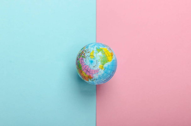Mini-Globus auf blau-rosa Pastellgrund. Ansicht von oben. Minimalismus - Foto, Bild