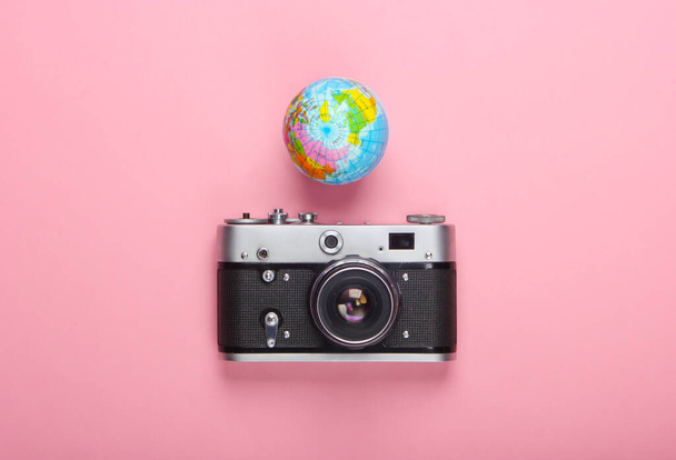 Tourismus und Reisekonzept. Globus, Kamera auf rosa Pastellgrund. Ansicht von oben. Flache Lage - Foto, Bild