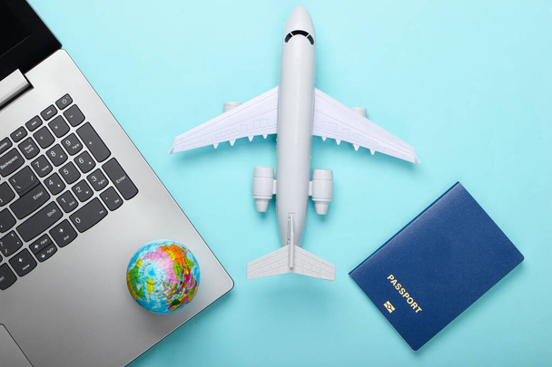 Viajar a vida. Reserva online. Emigração. Laptop, globo, avião e passaporte. Acessórios turísticos em fundo azul. Vista superior. Depósito plano - Foto, Imagem