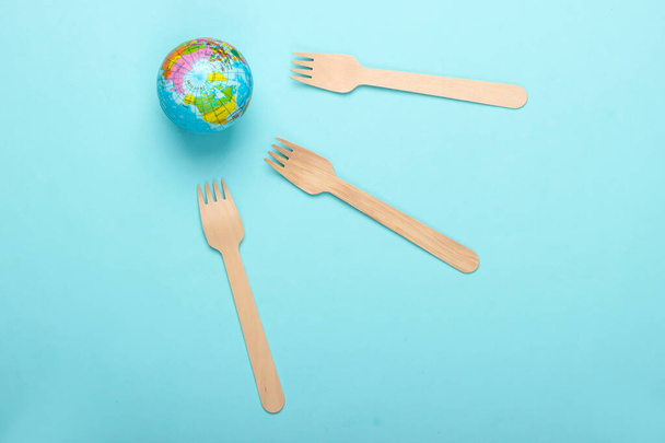 Nature morte écologique. Concept plastique libre. Globe avec fourchettes en bois sur fond bleu. Vue du dessus - Photo, image