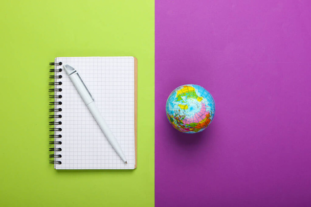 Globus und Notizbuch auf violettgrünem Hintergrund. Ansicht von oben. Minimalismus. Bildungskonzept, Geografie - Foto, Bild