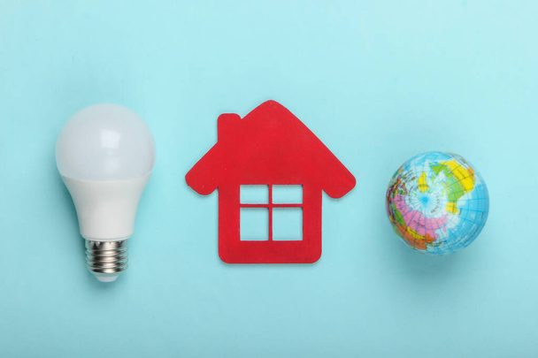 Eco, concetto di risparmio energetico. Figurine di casa con lampadina a led, globo su sfondo blu pastello. Vista dall'alto - Foto, immagini