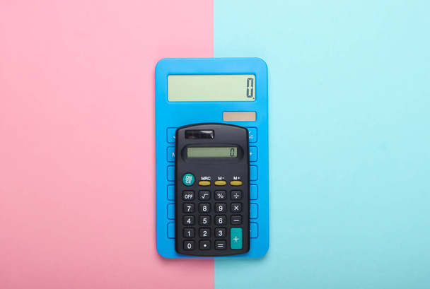 Dos calculadoras sobre fondo pastel rosa azul. Vista superior. - Foto, imagen