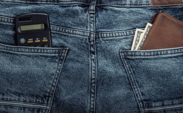 Laskin ja lompakko dollareita takana taskut sininen farkut - Valokuva, kuva