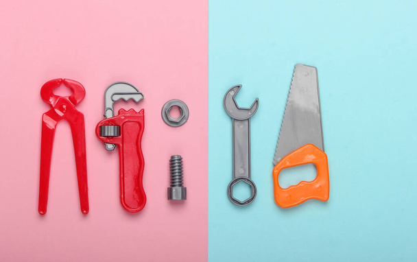 Kit di strumenti di lavoro per bambini in plastica su sfondo rosa pastello blu. Giocattoli. Vista dall'alto - Foto, immagini