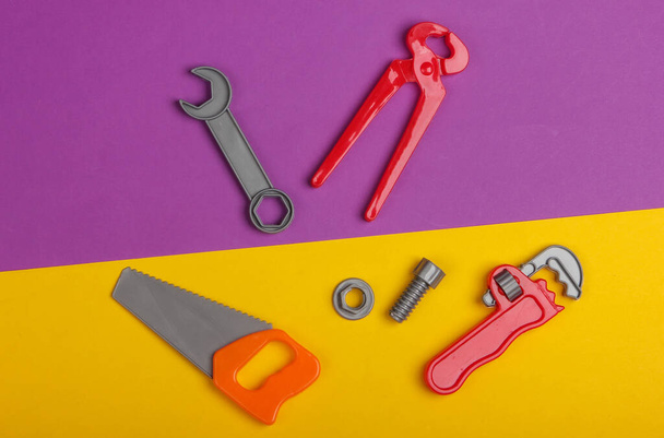 Kit di strumenti di lavoro per bambini in plastica su sfondo giallo porpora. Giocattoli. Vista dall'alto - Foto, immagini