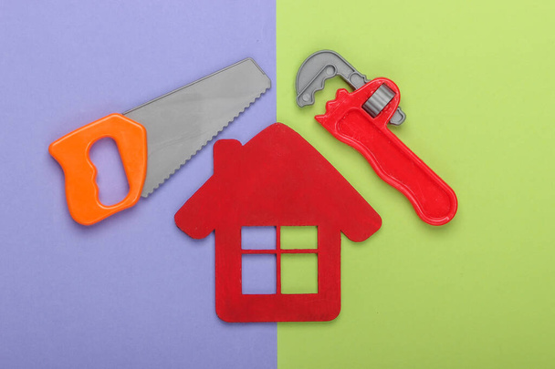 ホーム修理の概念や家の建設。ハウスフィギュア、紫緑の背景におもちゃの作業ツール。トップ表示 - 写真・画像
