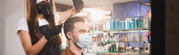 парикмахер в латексных перчатках и щит для лица, стригущий волосы человека в медицинской маске, баннер - Фото, изображение