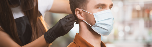 перукар в латексній рукавичці, що ріже волосся клієнта в медичній масці, банер
 - Фото, зображення