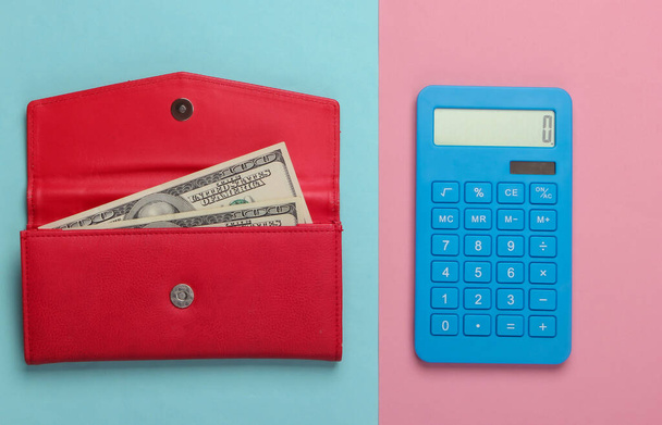 Aile bütçesini yönet. Alışveriş maliyetleri. Mavi hesap makinesi ve pembe mavi pastel arka planda dolar banknotları olan kırmızı deri cüzdan. Üst görünüm - Fotoğraf, Görsel