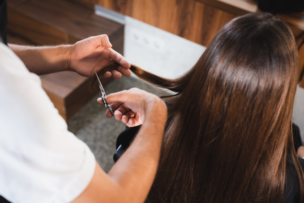 barber cutting hair of woman on blurred foreground - Фото, зображення