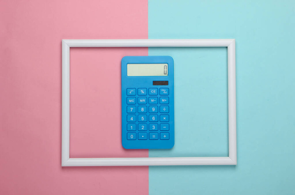 Calculadora em uma moldura branca no fundo azul rosa. Foto de arte conceitual. Vista superior. Minimalismo - Foto, Imagem