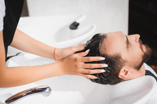 hairdresser washing hair of client in barbershop - Fotó, kép