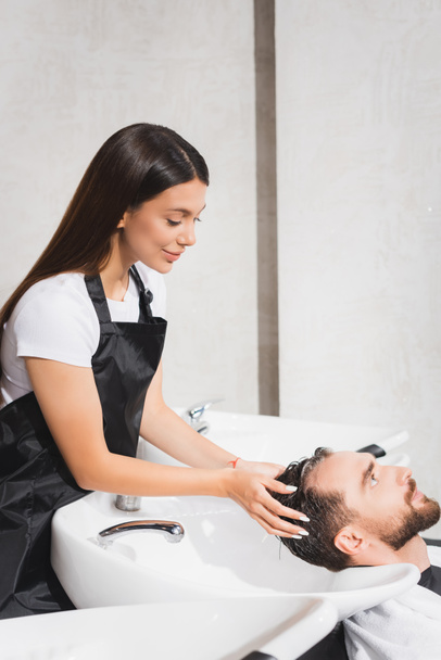 salon de coiffure souriant laver les cheveux du client dans le salon de coiffure - Photo, image