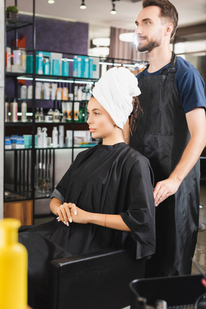 barbe barbier debout derrière femme avec les cheveux enveloppés dans la serviette - Photo, image