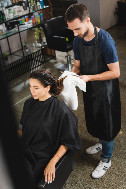 vista de ángulo alto del peluquero limpiando el cabello de la mujer con la toalla, borrosa primer plano - Foto, Imagen