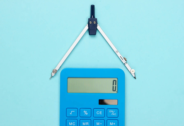 Calcolatrice e bussola su sfondo blu. Vista dall'alto - Foto, immagini