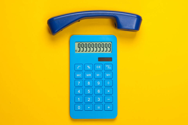 Calculadora con teléfono móvil de oficina sobre fondo amarillo. Vista superior - Foto, imagen