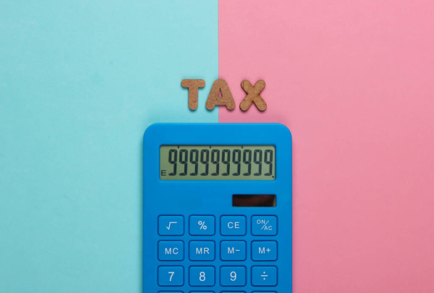 Калькулятор со словом налог на розовый синий пастельный фон. Вид сверху - Фото, изображение