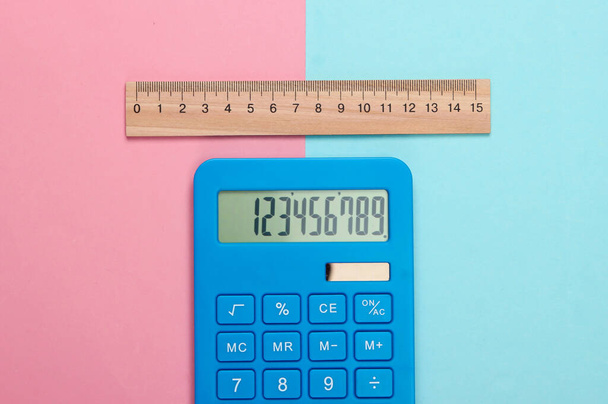 Calculadora y regla de madera sobre fondo pastel azul rosado. Concepto educativo. Vista superior - Foto, Imagen