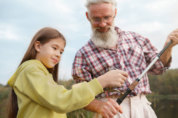 Mignon jeune fille profiter de l'apprentissage de la pêche de son grand-père - Photo, image