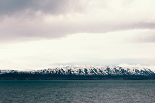 Krajobraz morski w pochmurny jesienny dzień ze śnieżnymi górami w tle - Zdjęcie, obraz