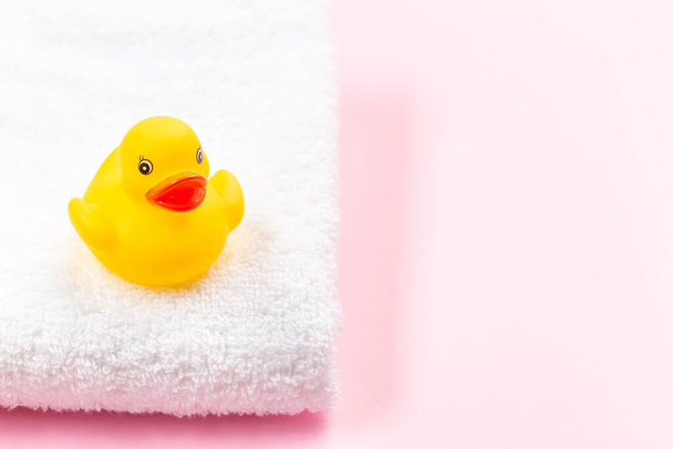 One rubber duck on a white terry bath towel, pink background with place for copy space, horizontal  - Foto, imagen