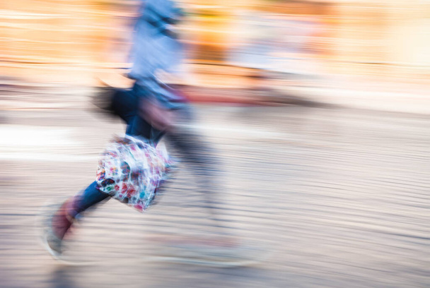 Motion blurred figure of a woman with a shopping bag on the city street - Photo, Image