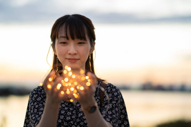 Aasialainen nuori nainen käärimällä valaistus valo molemmin käsin - Valokuva, kuva