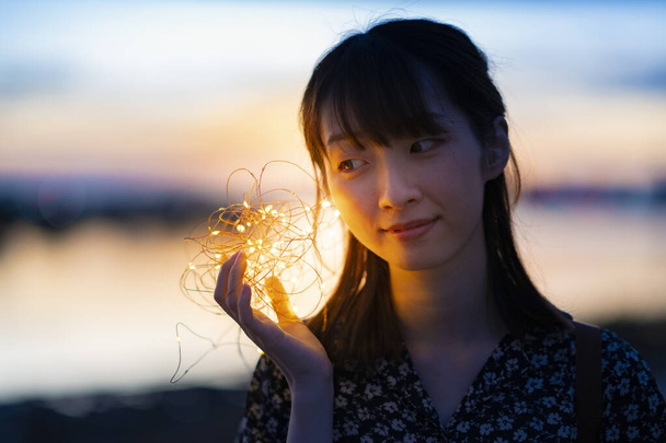 Una joven que acerca las luces de iluminación a su oído - Foto, Imagen