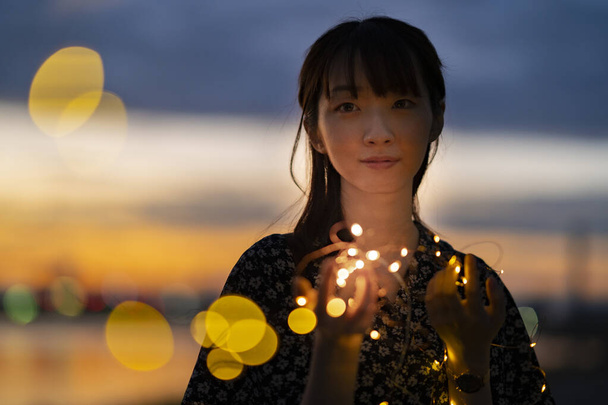 Asiática joven mujer mirando las luces de iluminación en la tarde - Foto, Imagen