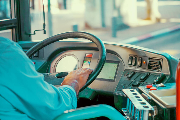 Concept van het stuurwiel van de buschauffeur en de rijdende passagiersbus. Handen van de bestuurder in een moderne bus door te rijden - Foto, afbeelding
