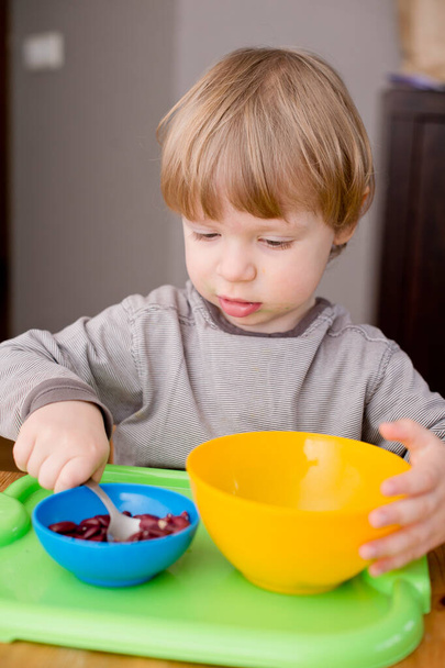 Boy sorting kidney beans from white beans. Montessori concept. Preschool implement for early education. Fine motoric skills and attention training exercise. DIY kid play at home concept. - Photo, Image