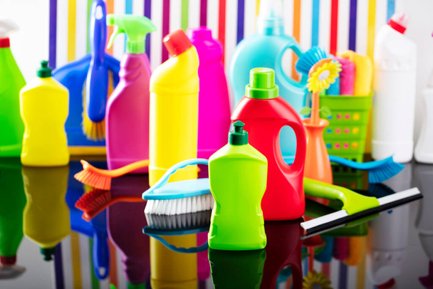 Temat sprzątania domu i biura. Kolorowy zestaw butelek z błyszczącymi cieczami na tle w postaci kolorowych pasków. - Zdjęcie, obraz