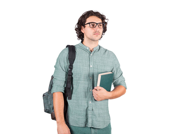Portré egy diákról, aki könyvet tart a mellkasához, és vállán cipeli a hátizsákját. Vonzó barna fiatalember, hosszú göndör frizura, szemüveges, vissza az iskolába elszigetelt fehér. - Fotó, kép