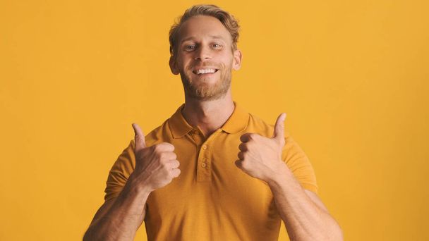 Handsome cheerful blond bearded man showing thumbs up on camera over colorful background. Well done expression - Photo, Image