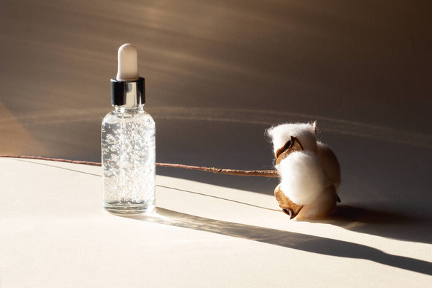 Eine kosmetische oder medizinische Glasflasche mit Serum oder Öltropfen. Hautpflegekonzept. Natürliches hartes Licht, tiefe Schatten. - Bild - Foto, Bild