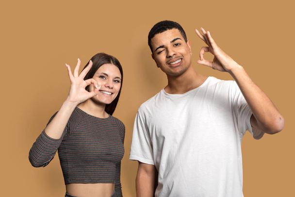 Photo of amazing couple showing okey symbols agree with good quality product wear casual outfit isolated brown color background - Foto, immagini