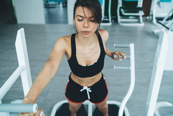Slim woman in active wear and sexy figure breathing during workout losing weight and calories, beautiful concentrated hipster girl using equipment training muscles keeping perfect body shape - Foto, afbeelding