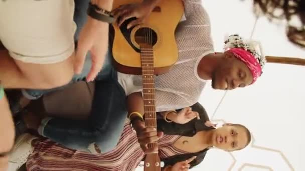 Pozvednuté záběry kamarádů, jak se odchlazují na akustickou kytaru, jak tancují a zpívají - Záběry, video
