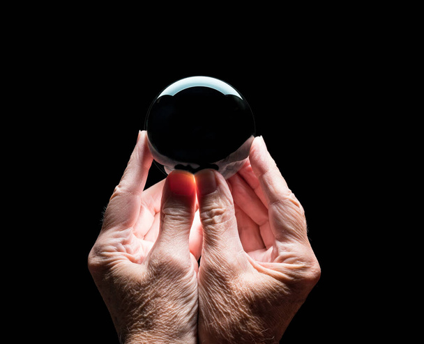Ręce trzymające kryształową kulę prognozującą z czarnym środkiem, aby umożliwić łatwe kompozyty - Zdjęcie, obraz